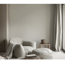 Wohnzimmer mit Sessel, Hocker, Beistelltisch, Vorhang und Dekoration für eine helle und freundliche Atmosphäre.