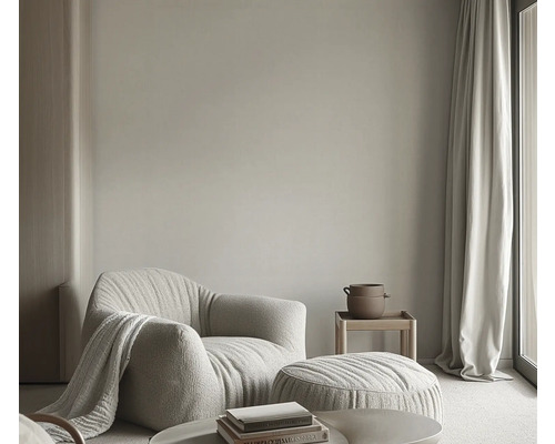 Wohnzimmer mit Sessel, Hocker, Beistelltisch, Vorhang und Dekoration für eine helle und freundliche Atmosphäre.