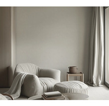 Wohnzimmer mit Sessel, Hocker, Beistelltisch und Vorhängen für eine helle und einladende Atmosphäre.