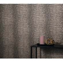 Detailaufnahme einer Wand mit Reptilienlederoptik-Tapete, einem Kerzentablett mit Kerze und Blumenschmuck