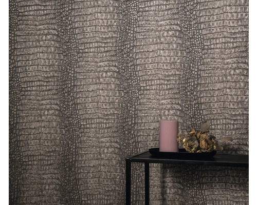 Detailaufnahme einer Wand mit Reptilienlederoptik-Tapete, einem Kerzentablett mit Kerze und Blumenschmuck