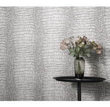 Nahaufnahme einer Wand mit Krokodilleder-Tapete, einem Tisch und Blumenvase