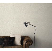 Wohnzimmer mit heller Mauerwerk-Optik Tapete, braunem Sofa und Stehlampe