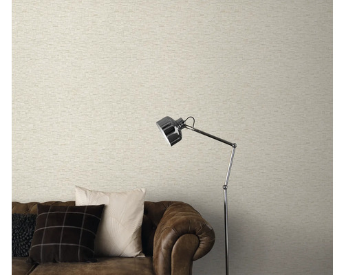 Wohnzimmer mit heller Mauerwerk-Optik Tapete, braunem Sofa und Stehlampe