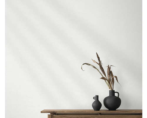 Zwei dunkle Vasen mit Pflanzendekoration auf einem Holztisch