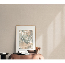 Szene mit einem gerahmten Bild mit Pflanzenmotiven auf einem Hocker vor einer Textiltapete.