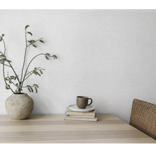 Dekoratives Stillleben mit Vase, Zweigen, Tasse und Büchern auf einem Holztisch.