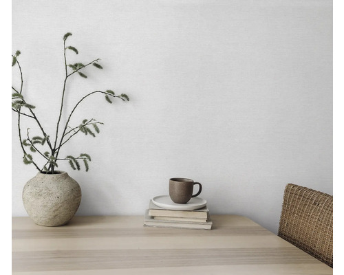 Dekoratives Stillleben mit Vase, Zweigen, Tasse und Büchern auf einem Holztisch.