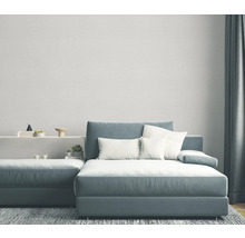 Wohnzimmer mit graublauem Ecksofa, weißen Kissen und grauem Teppich