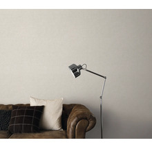 Wohnzimmer mit braunem Ledersofa, Kissen, Stehlampe und beiger Tapete