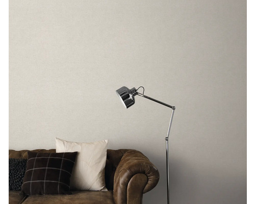 Wohnzimmer mit braunem Ledersofa, Kissen, Stehlampe und beiger Tapete