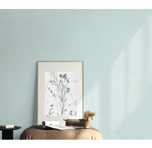 Nahaufnahme einer Wand mit einer hellen Tapete, einem gerahmten Bild mit Blumenmuster und einer Dekofigur