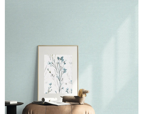 Nahaufnahme einer Wand mit einer hellen Tapete, einem gerahmten Bild mit Blumenmuster und einer Dekofigur