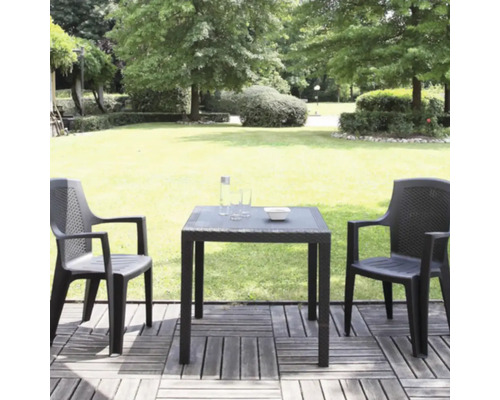 Gartenmöbel-Set aus Kunststoff in Rattan-Optik mit zwei Stühlen und einem quadratischen Tisch auf einer Holzterrasse in einer hellen Gartenanlage.