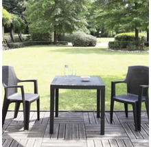 Gartenmöbel-Set aus Kunststoff in Rattan-Optik mit zwei Stühlen und einem quadratischen Tisch auf einer Holzterrasse in einer hellen Gartenanlage.