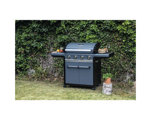 Gasgrill mit vier Brennern, Seitentischen und Schrank vor einer grünen Hecke