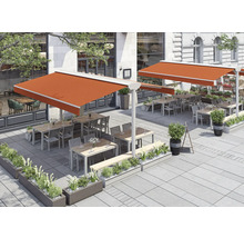 Terrasse mit Markisen, Tischen, Stühlen und Bepflanzung vor einem Gebäude