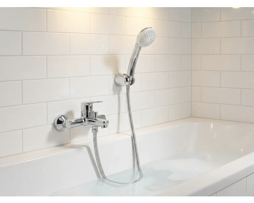 Badezimmer mit Badewanne, Armatur und Handbrause vor Wandfliesen