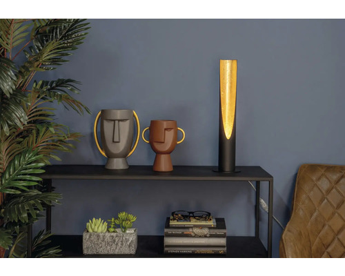 Dekorative Szene mit einer Tischlampe, zwei Vasen mit Gesichtern, Zimmerpflanzen und Büchern auf einem Regal