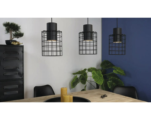 Drei Hängelampen mit schwarzem Drahtkäfig über einem Esstisch in einem hellen Raum