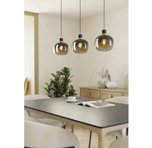 Drei Pendelleuchten mit runden Glasschirmen über einem Esstisch.