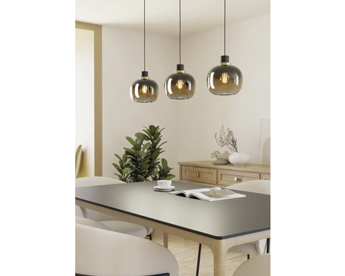 Drei Pendelleuchten mit runden Glasschirmen über einem Esstisch.