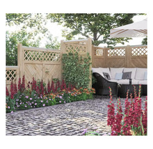 Garten mit Holzzaun, Pflanzen und Sitzbereich mit Gartenmöbeln unter einem Sonnenschirm