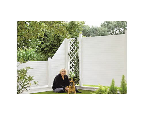 Frau mit Hund vor einem weißen Gartenzaun