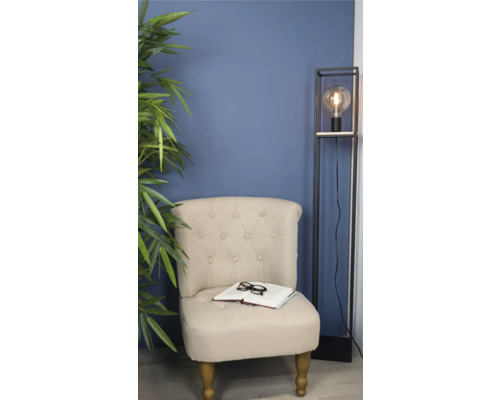 Sessel mit Buch und Brille neben Stehlampe und Zimmerpflanze