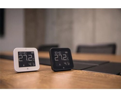 Zwei digitale Thermometer und Hygrometer in Weiß und Schwarz auf einem Holztisch, die 27,2 Grad Celsius und 41 Prozent Luftfeuchtigkeit anzeigen.