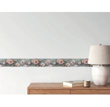Tapetenborte mit rosa Blumenmuster an einer Wand über einer Holzkommode mit einer Tischleuchte.