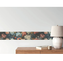 Tapetenbordüre mit floralem Muster an einer Wand über einem Sideboard aus Holz mit Lampe und Buch.