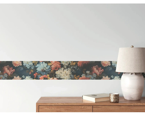 Tapetenbordüre mit floralem Muster an einer Wand über einem Sideboard aus Holz mit Lampe und Buch.
