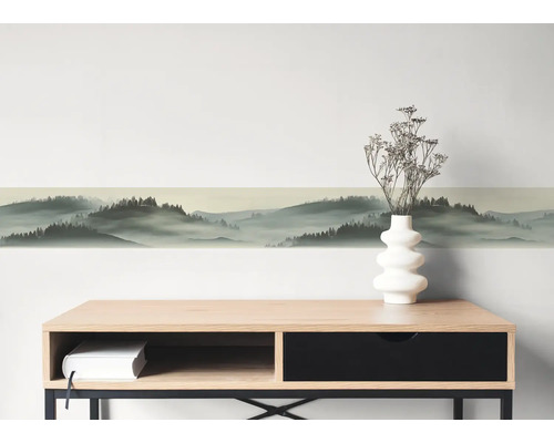 Selbstklebende Wandbordüre mit Waldlandschaft und Nebeleffekt über einem Sideboard.