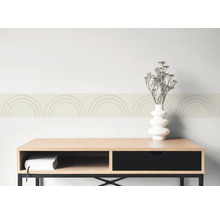 Tapetenbordüre mit Bogenmuster an einer Wand über einem Sideboard aus Holz mit Vase und getrockneten Blumen.