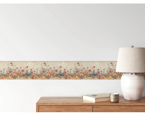 Tapetenborte mit Mohnblumenmuster an einer Wand über einer Holzkommode mit Tischlampe in einem hellen Raum.