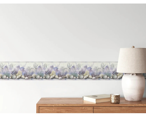Tapetenbordüre mit maritimen Motiven wie Muscheln und Korallen in Aquarell-Optik auf einer hellen Wand über einer Holzkommode.