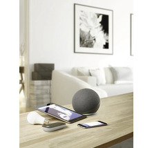 Aufnahme eines Wohnraums mit Smart Home Geräten wie Lautsprecher, Tablet, Smartphone und Leuchtmittel auf einem Tisch.