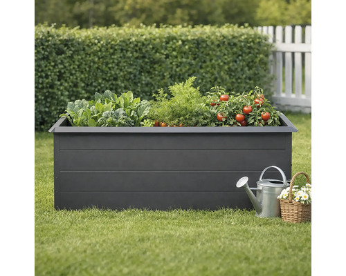 Hochbeet mit Gemüse, Gießkanne und Korb mit Blumen im Garten.