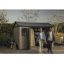 Gartenszene mit Gerätehaus, einer Frau und einem Mann, die Werkzeuge und Holz tragen