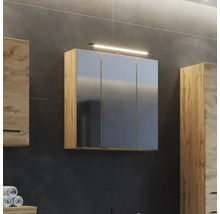 Dreitüriger Spiegelschrank in Eichenoptik mit Beleuchtung an einer dunklen Wand im Badezimmer neben weiteren Badmöbeln aus Holz.