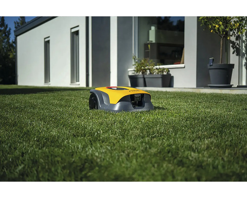 Gelber Rasenmähroboter auf einer Rasenfläche vor einem Haus