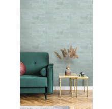 Wohnzimmer mit grüner Couch, Couchtisch und gemusterter Tapete.