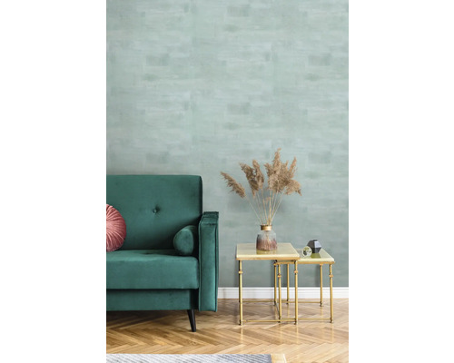 Wohnzimmer mit grüner Couch, Couchtisch und gemusterter Tapete.