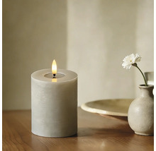 Dekorative LED Kerze mit Flamme und einer einzelnen Blume in einer Vase auf einem Tisch