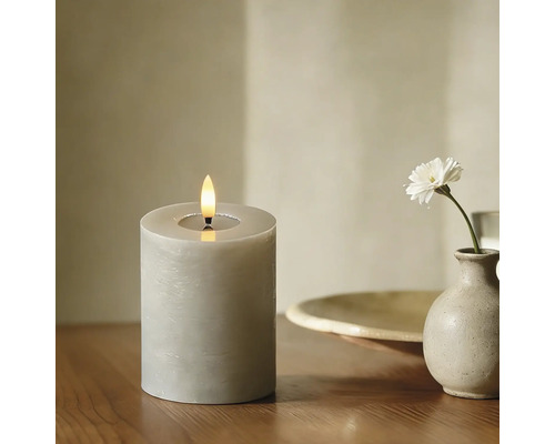 Dekorative LED Kerze mit Flamme und einer einzelnen Blume in einer Vase auf einem Tisch