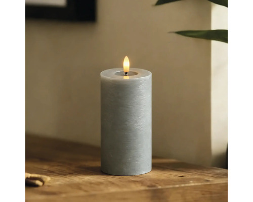 Dekorative graue LED Stumpenkerze mit simulierter Flamme auf einem Holztisch