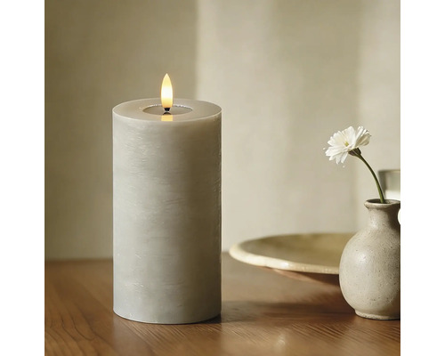 Dekorative LED-Kerze auf einem Tisch neben einer Blume in einer Vase