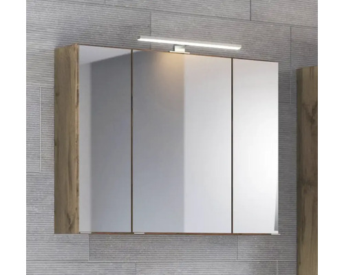 Dreitüriger Spiegelschrank mit LED-Aufsatzleuchte und Korpus in Holzoptik an einer grau gefliesten Wand.