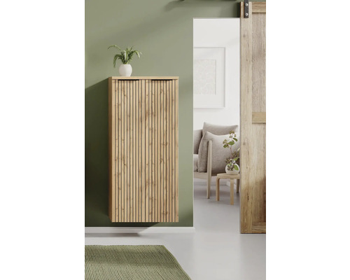 Moderner Hängeschrank aus Holz mit Lamellenfront in einem hellen, geordneten Wohnraum mit Blick in ein angrenzendes Zimmer mit Sessel.